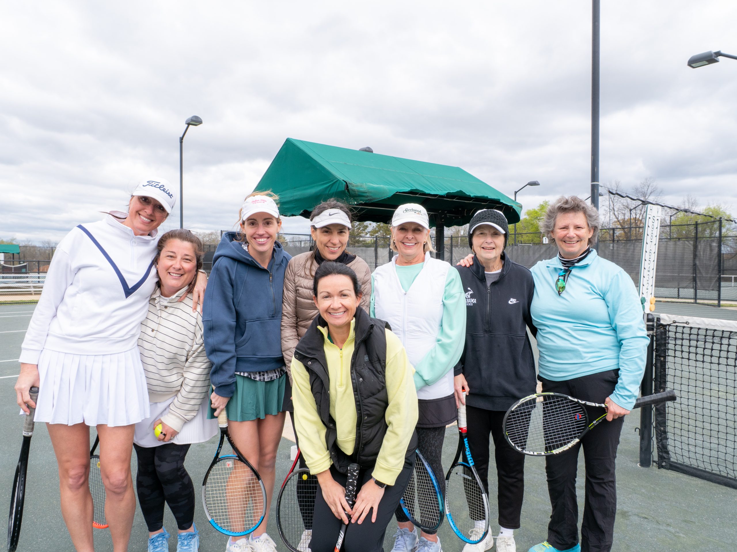 A group of smiling women on a tennis court