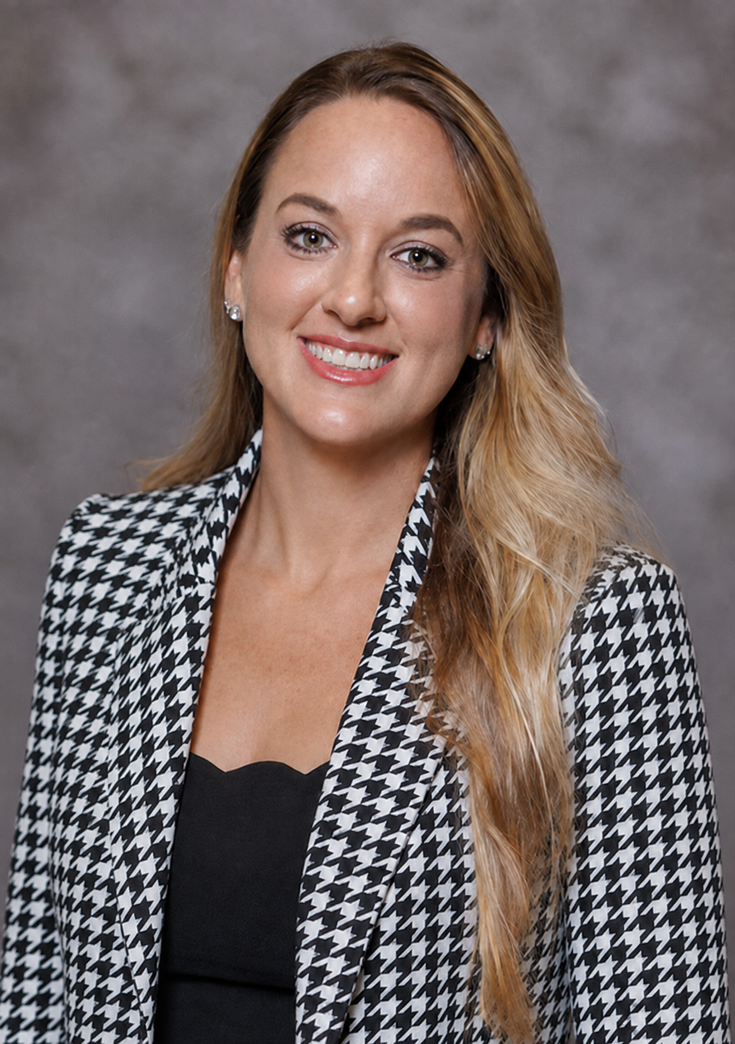 Chelsea Ale faculty Member in the Department of Human Nutrition, Hospitality and Sport Management with with and black houndstooth jacket on with black shirt.